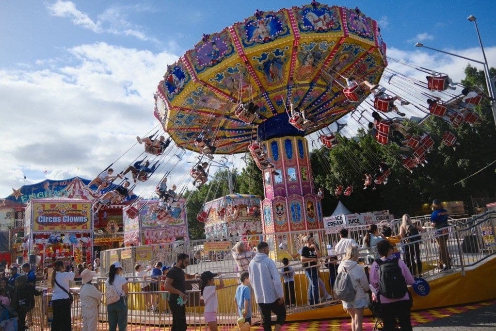 Crowds moving through a busy showground at night